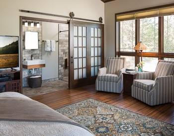 Two striped wing back chairs with a view of the stone bathroom, large windows  with a view of the mountains